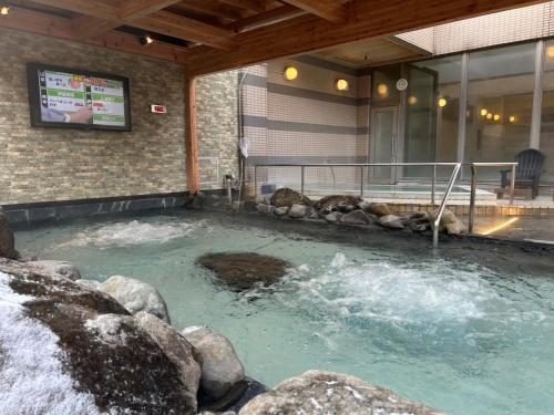 a hot tub in a building with a tv at LiVEMAX RESORT Hakodate Greenpia Onuma in Mori