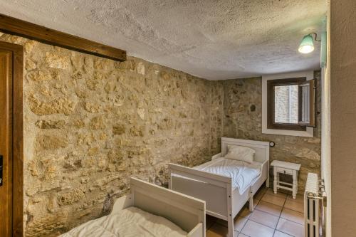 two beds in a room with a stone wall at Habitacions Mas Fuselles in Girona