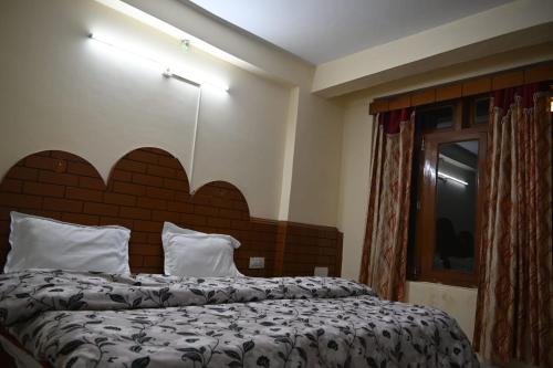 a bedroom with a large bed with a large headboard at Taj Guest House in Manāli