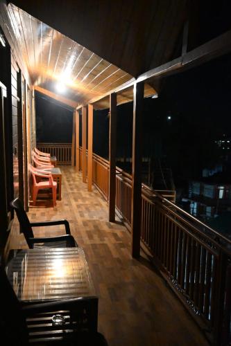 a balcony with a table and chairs at night at Taj Guest House in Manāli