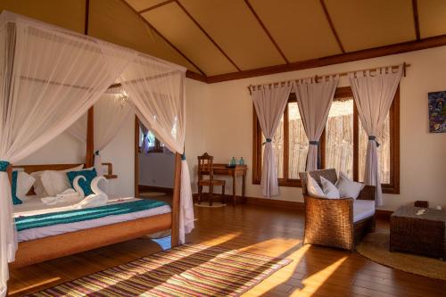 a bedroom with a bed and a chair in a room at Pole Pole Bungalows in Utende