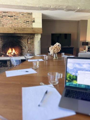 un ordinateur portable assis sur une table avec une cheminée dans l'établissement Le Manoir de la campagne, à Yébleron
