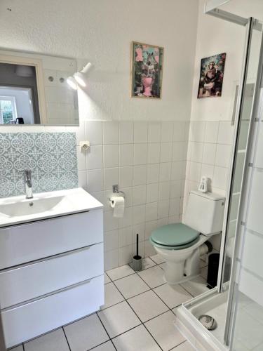 La salle de bains est pourvue de toilettes vertes et d'un lavabo. dans l'établissement Le Longbeach 1, à Longueville