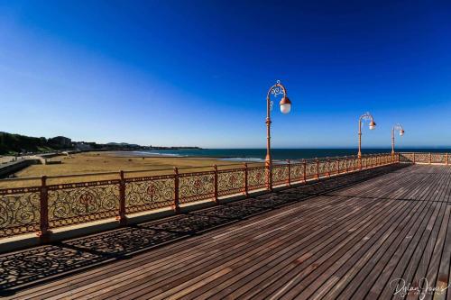 a boardwalk with lights and a beach and a pier at Pendle House - Apt 4 - 3 min walk to beach & Shops! in Colwyn Bay