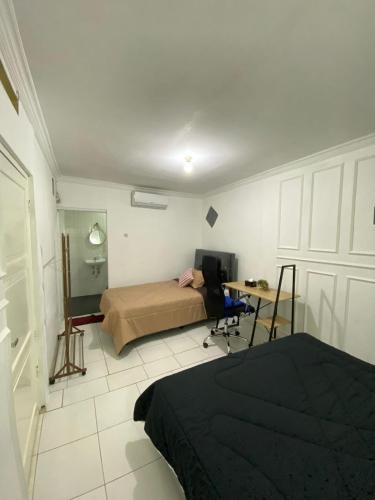 ein Schlafzimmer mit einem Bett und einem Schreibtisch darin in der Unterkunft Rumahtata Homestay in Purwokerto