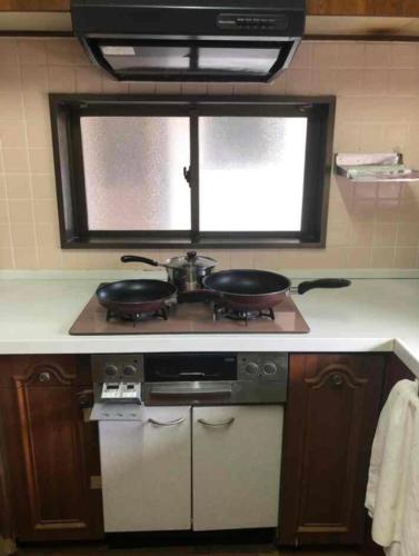 a kitchen with two pans on top of a stove at Zamami Chura Dreamz in Zamami