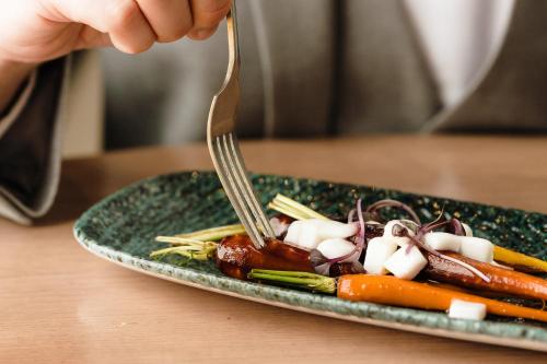 a person eating a plate of food with a fork at Edgbaston Park Hotel Birmingham in Birmingham