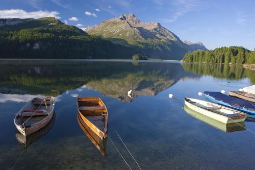 two boats on a lake with a mountain in the background at Hotel Schweizerhof Sils Maria, a Faern Collection Hotel in Sils Maria