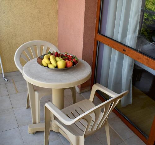 a bowl of fruit on a table next to a chair at Julia Vigo Panorama apartments in Nesebar