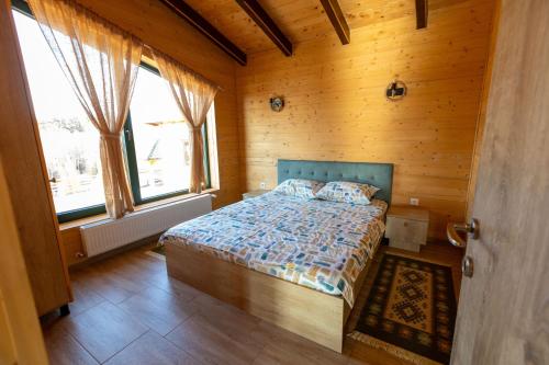 a bedroom with a bed with wooden walls and windows at Casa Rustică in Călăţele