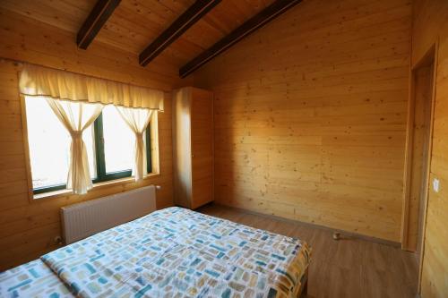 a bedroom with a bed and two windows at Casa Rustică in Călăţele