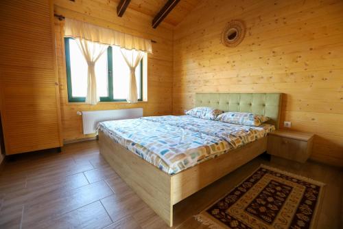 a bedroom with a bed in a wooden room at Casa Rustică in Călăţele