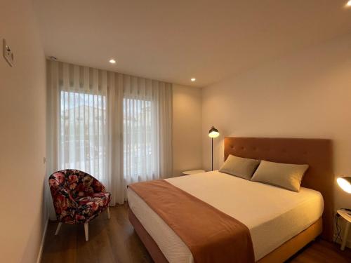 a bedroom with a bed and a chair and a window at Estrela Santa Ana Cova da Iria in Fátima