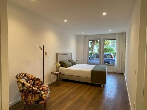 a bedroom with a bed and a chair and a window at Estrela Santa Ana Cova da Iria in Fátima