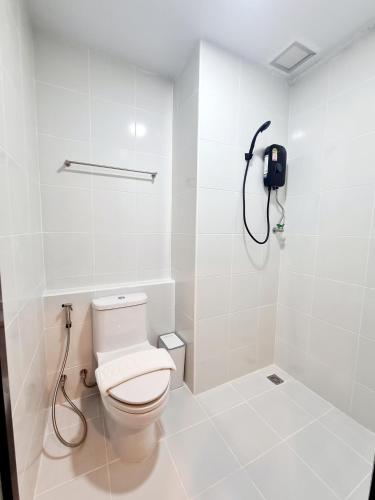 a white bathroom with a toilet and a phone at Hometown Stays Hatyai in Hat Yai