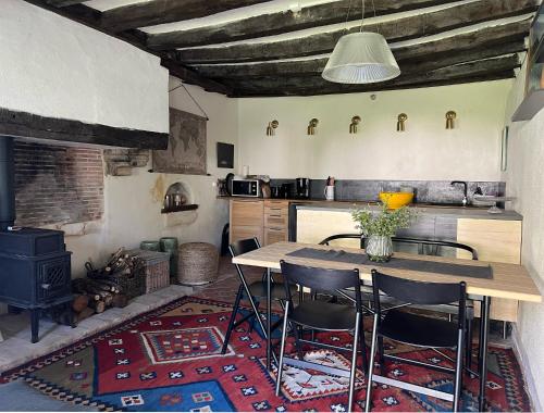une cuisine avec une table, des chaises et une cuisinière dans l'établissement Gîte Moulin des Arts, à Loché-sur-Indrois