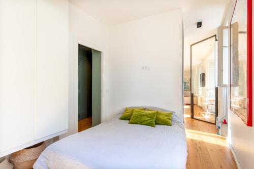 - une chambre avec un lit blanc et des oreillers verts dans l'établissement Loft Flore, à Paris