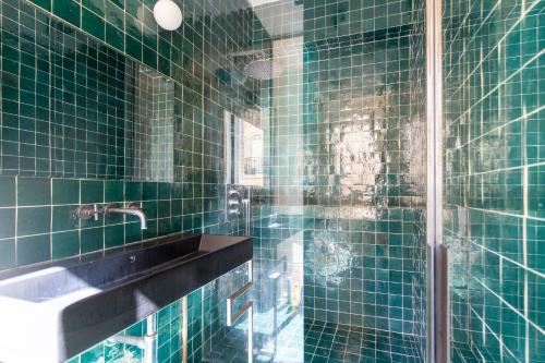 une salle de bain carrelée verte avec un lavabo et un miroir dans l'établissement Loft Flore, à Paris