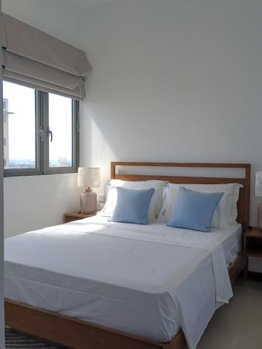a bedroom with a large white bed with blue pillows at Colombo, Trizen Luxury Apartments, Sri Lanka in Colombo