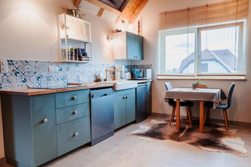 une cuisine avec des placards bleus, une table et une fenêtre dans l'établissement Appartement - Atelier Ayurvédique - Aline et Oliver, à Orschwiller