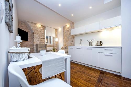 a kitchen with white cabinets and a table and chairs at Luna Rooms and Studios Rovinj in Rovinj