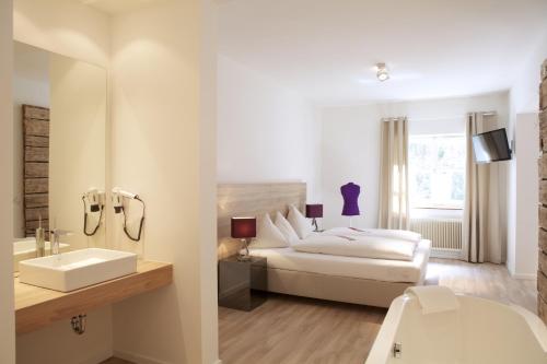 a white bedroom with a bed and a sink at Hotel Krone 1512 in Salzburg