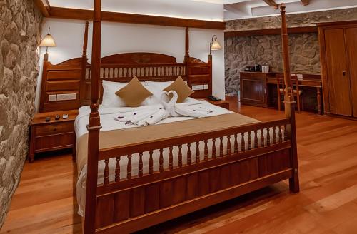 a bedroom with a large bed with a wooden frame at Le Montfort Resort in Munnar