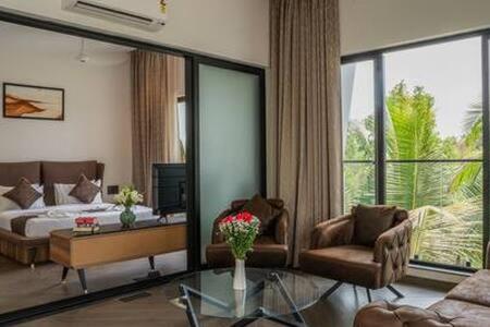 a hotel room with a bed and a living room at Peacock View 4 BHK Pvt Pool & Jacuzzi at Saligao in Saligao