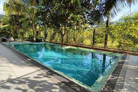 a blue swimming pool with trees and a fence at Peacock View 4 BHK Pvt Pool & Jacuzzi at Saligao in Saligao