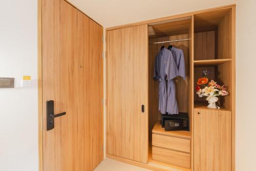 a closet with a wooden door and a robe at VELA be Bangkok Siam in Bangkok