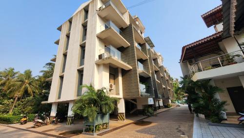 a tall building with palm trees in front of it at 2bhk Bruno Nera Candolim 10 mins to beach in Nerul