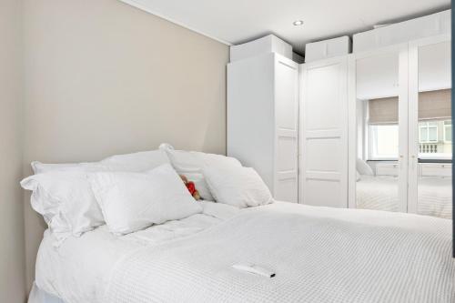 a white bedroom with a white bed with white pillows at Modern apartment in Bergen city centre in Bergen