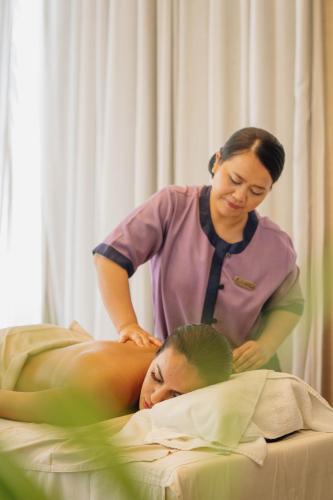 a woman is laying on a bed with a womanorative practition at Banyan Tree Tamouda Bay in Fnidek