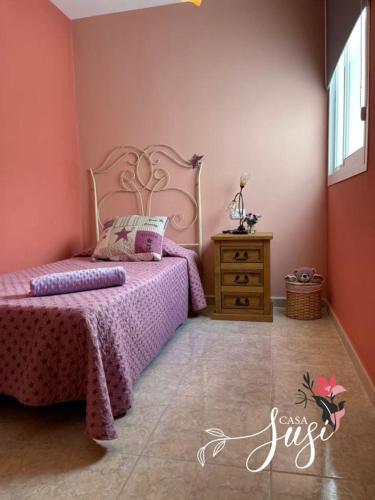 a pink bedroom with a bed and a wooden dresser at Casa Susi in Tazacorte
