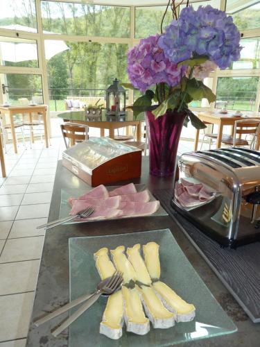 a table topped with slices of cheese and a vase of purple flowers at Hôtel La Colombiere Cantal in Massiac
