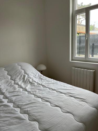 un grand lit blanc dans une chambre avec une fenêtre dans l'établissement Appartement Fort Mahon 250m de la plage, à Fort-Mahon-Plage