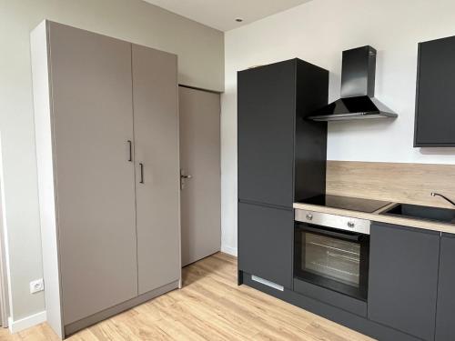 - une cuisine avec des placards gris, un évier et une cuisinière dans l'établissement Appartement Fort Mahon 250m de la plage, à Fort-Mahon-Plage