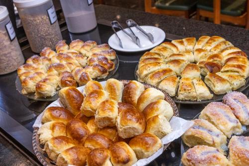 a bunch of different types of breads and pastries on a counter at Nikkey Palace Hotel in Sao Paulo