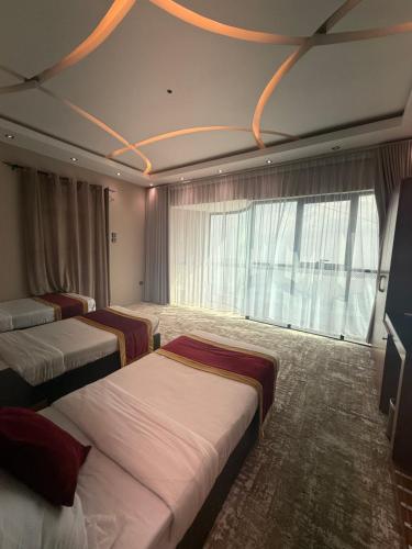 a hotel room with three beds and a large window at فندق فيفاء الفاخر in Fayfāʼ