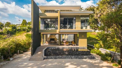 a woman sitting in a chair in front of a house at Merbrisa Rayong poolvilla 4BR - Ao khai beachfront in Mae Pim