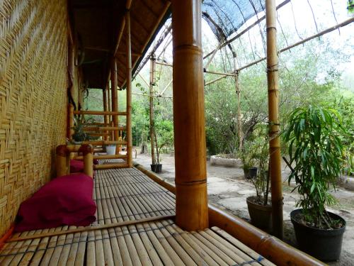 a porch with a bed in a room with trees at Uncle Hippie's Dream in Gili Meno