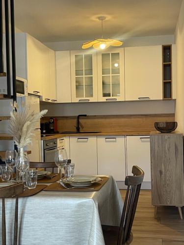 une cuisine avec des placards blancs et une table avec des verres dans l'établissement Petite maison de village, à Bastelica