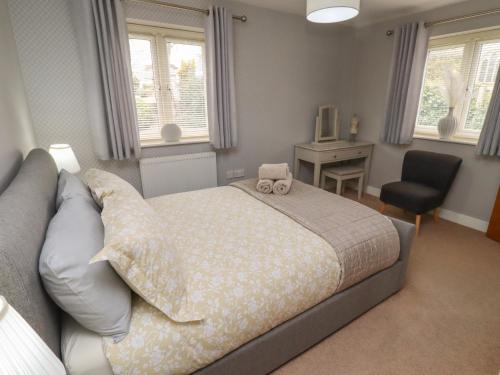 a bedroom with a bed and a chair and windows at Assisi Apartment in Alnmouth