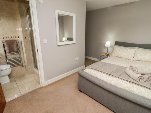 a bedroom with a bed and a bathroom with a shower at Assisi Apartment in Alnmouth