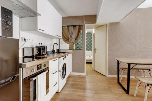 une cuisine avec des armoires blanches et une table et une salle à manger dans l'établissement Appartement raffine proche Parc de la Villette - 4P, à Paris