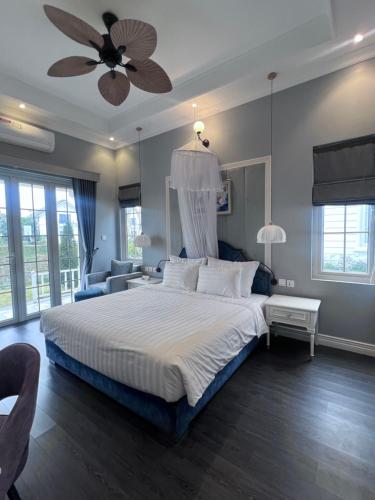 une chambre avec un grand lit avec un ventilateur de plafond dans l'établissement Prospera Haven - Vuon Vua Villa & Resort Thanh Thuy, à Phú Thọ