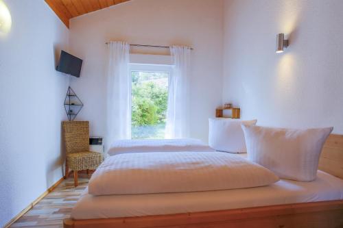 a white bedroom with two beds and a window at MöwenKieker mit Terrasse im Ferienpark Silz in Silz