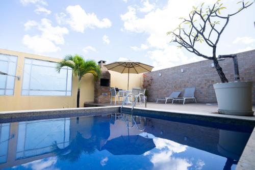 a swimming pool with an umbrella next to a building at Motel Scala in Salvador