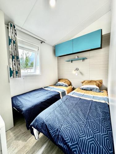 - 2 lits dans une chambre avec des draps bleus et blancs dans l'établissement Bungalow 3 chambres pour 6 pers avec Climatisation Camping 3 etoiles, à Samoëns