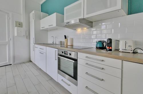 une cuisine blanche avec des armoires et des appareils blancs dans l'établissement Saint Genevieve Chic, à Lyon